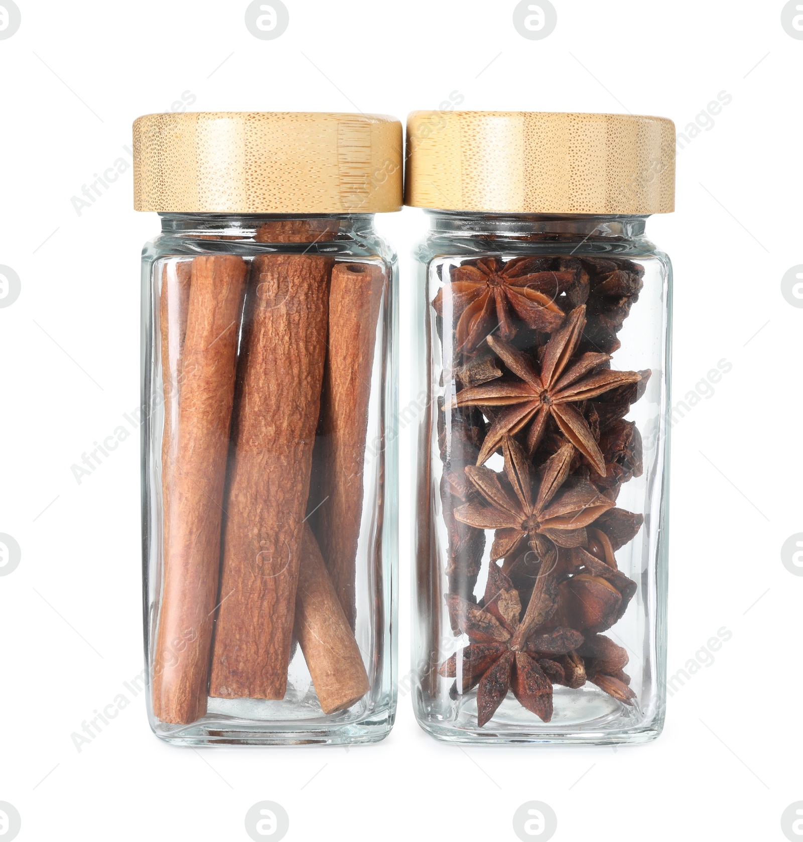 Photo of Cinnamon sticks and anise stars in glass jars isolated on white