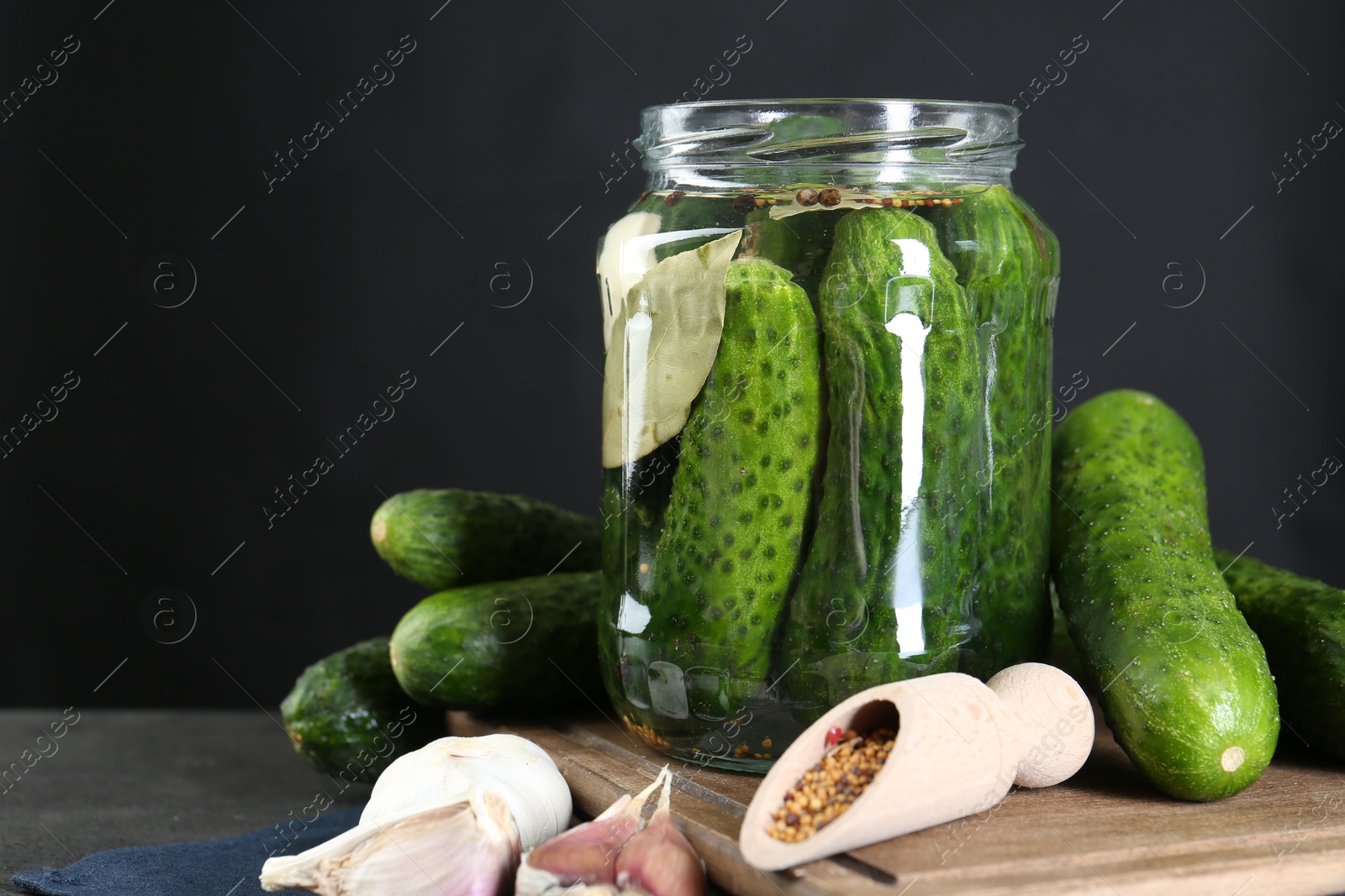 Photo of Making pickles. Fresh cucumbers and spices in jar on grey table