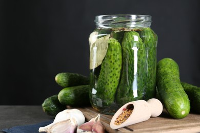 Photo of Making pickles. Fresh cucumbers and spices in jar on grey table