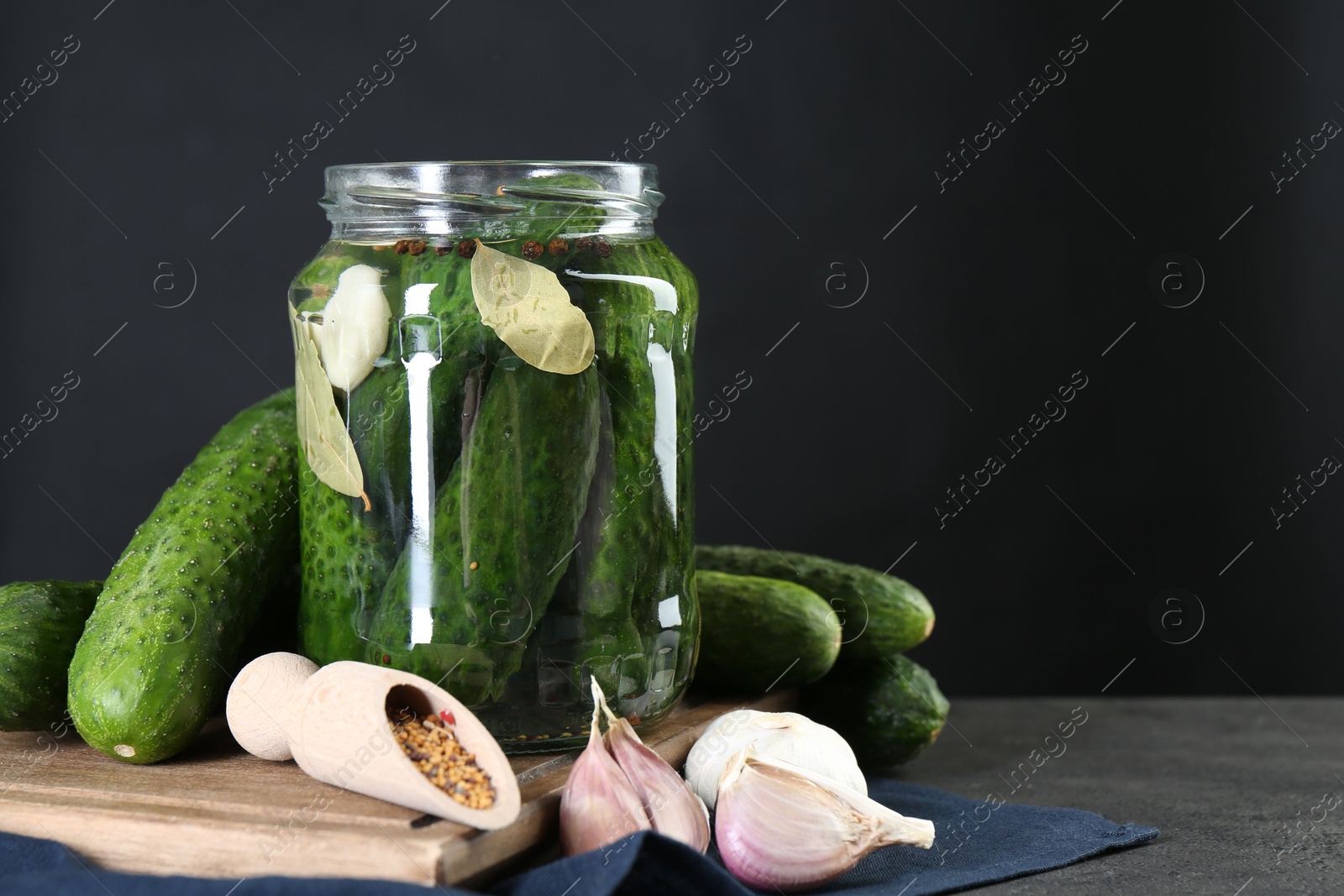 Photo of Making pickles. Fresh cucumbers and spices in jar on grey table. Space for text