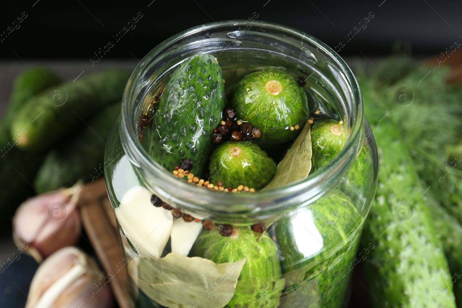 Photo of Making pickles. Fresh cucumbers and spices in jar, closeup