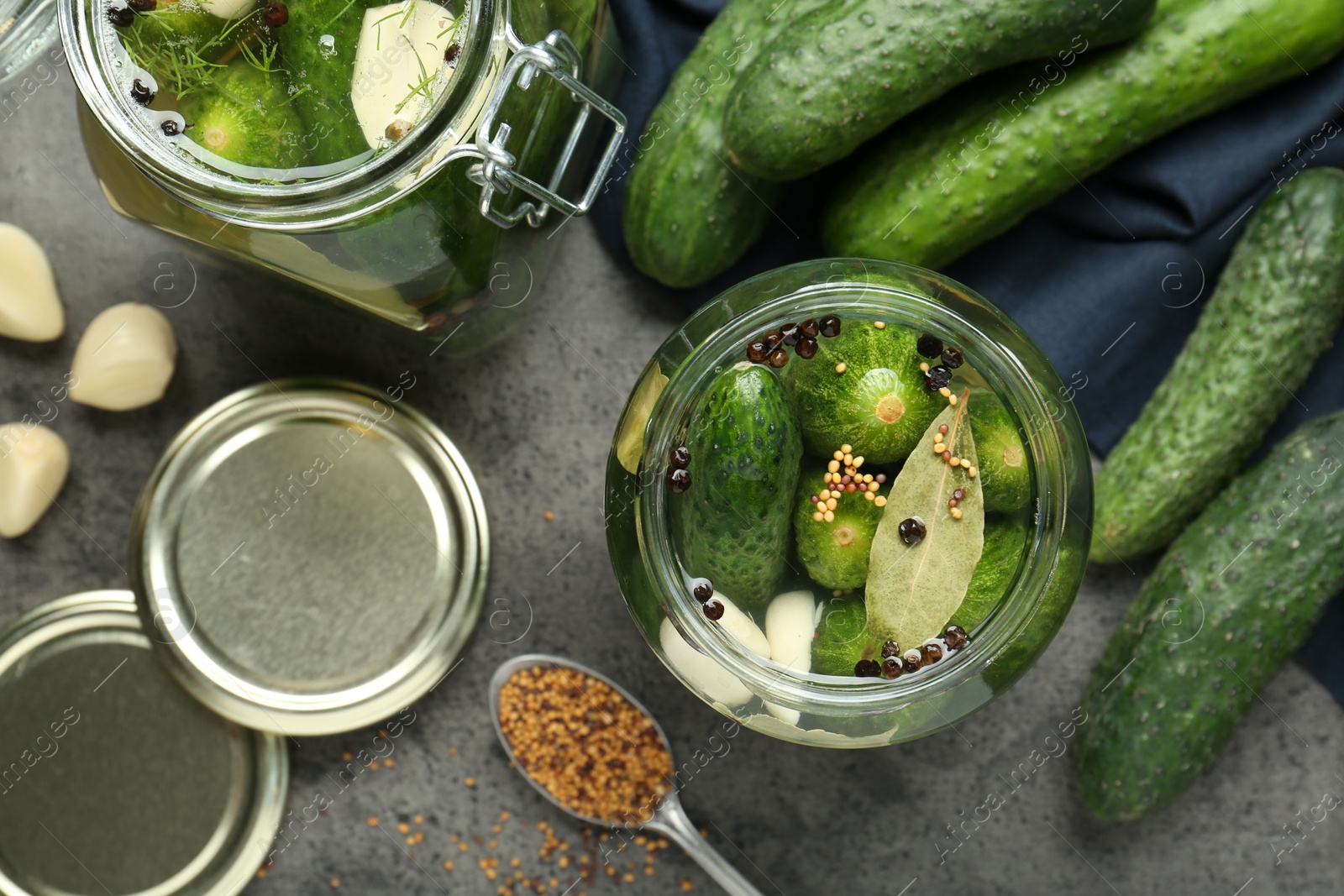 Photo of Making pickles. Fresh cucumbers and spices in jars on grey table, flat lay