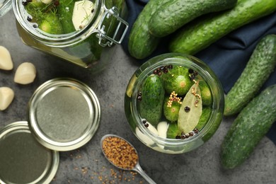 Photo of Making pickles. Fresh cucumbers and spices in jars on grey table, flat lay