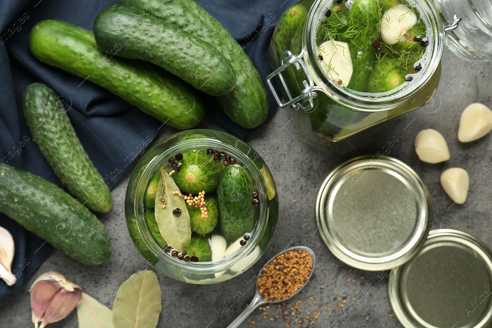 Photo of Making pickles. Fresh cucumbers and spices in jars on grey table, flat lay