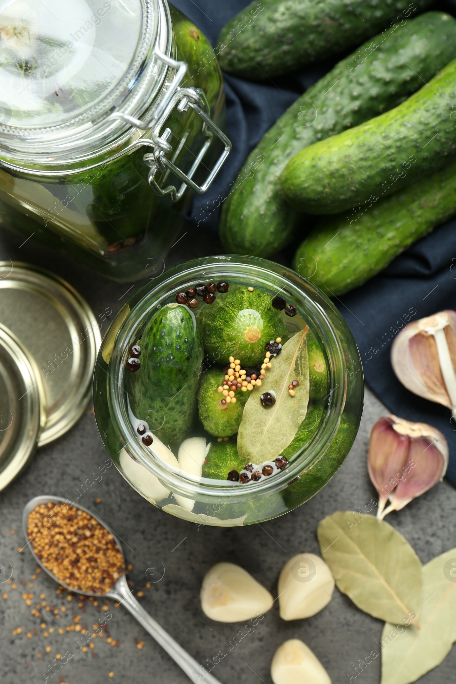 Photo of Making pickles. Fresh cucumbers and spices in jars on grey table, flat lay