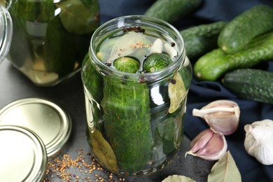 Photo of Making pickles. Fresh cucumbers and spices in jar on grey table