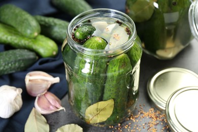 Photo of Making pickles. Fresh cucumbers and spices in jar on grey table