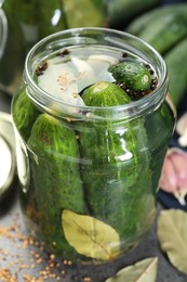 Photo of Making pickles. Fresh cucumbers and spices in jar on grey table