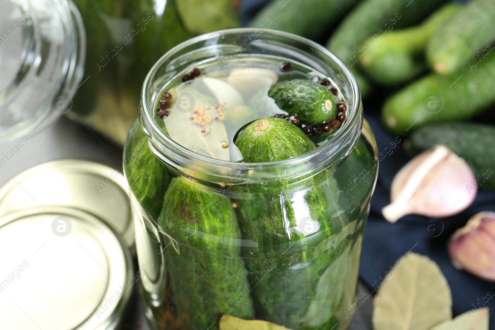 Photo of Making pickles. Fresh cucumbers and spices in jar on table, closeup