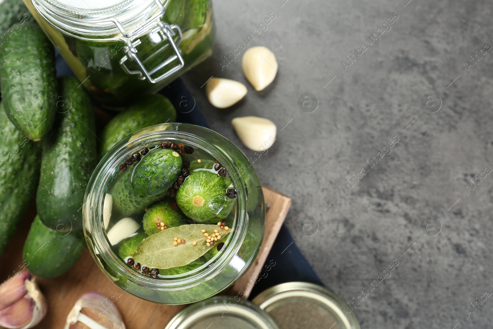 Photo of Making pickles. Fresh cucumbers and spices in jars on grey table, flat lay. Space for text