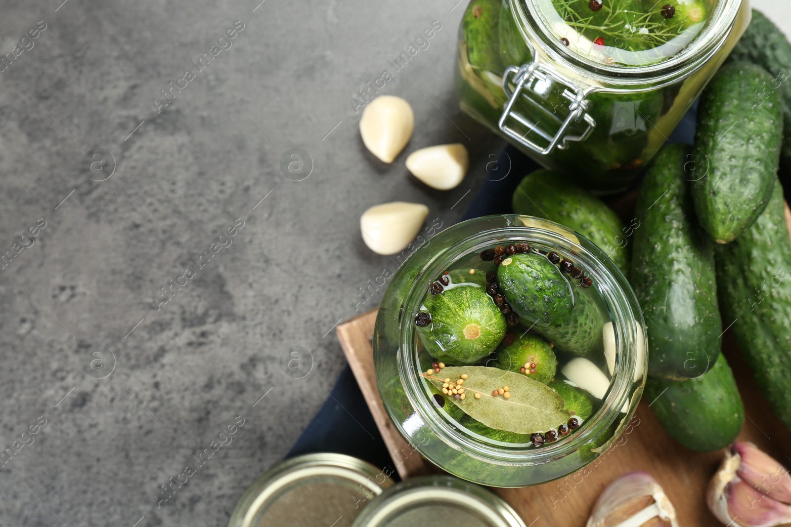 Photo of Making pickles. Fresh cucumbers and spices in jars on grey table, flat lay. Space for text