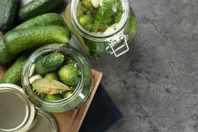 Photo of Making pickles. Fresh cucumbers and spices in jars on grey table, flat lay. Space for text