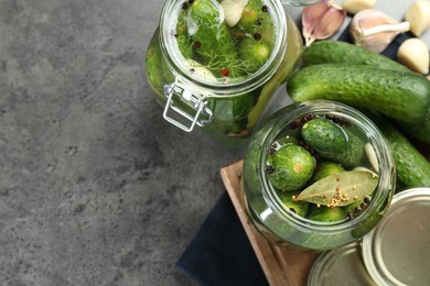 Photo of Making pickles. Fresh cucumbers and spices in jars on grey table, flat lay. Space for text