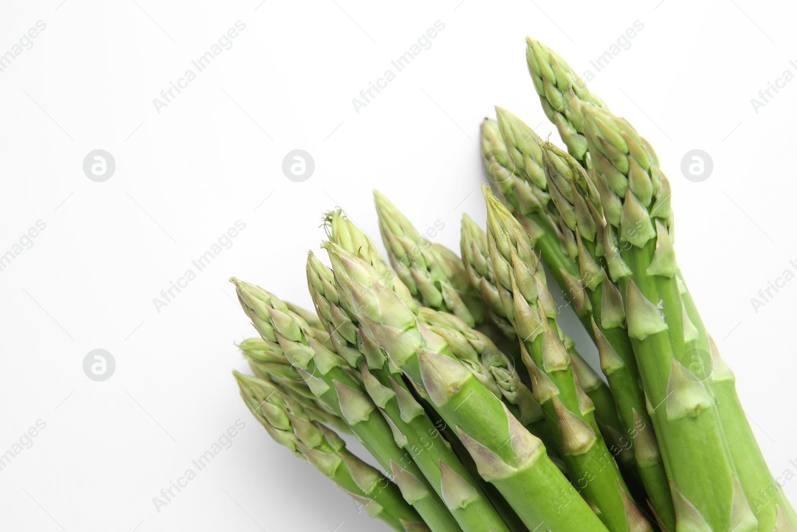 Photo of Fresh green asparagus stems on white table, top view. Space for text