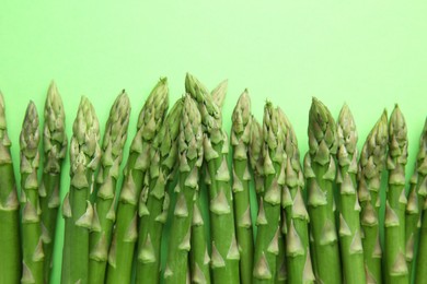 Photo of Fresh asparagus stems on green table, top view