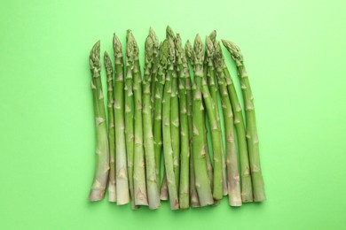 Photo of Fresh asparagus stems on green table, top view