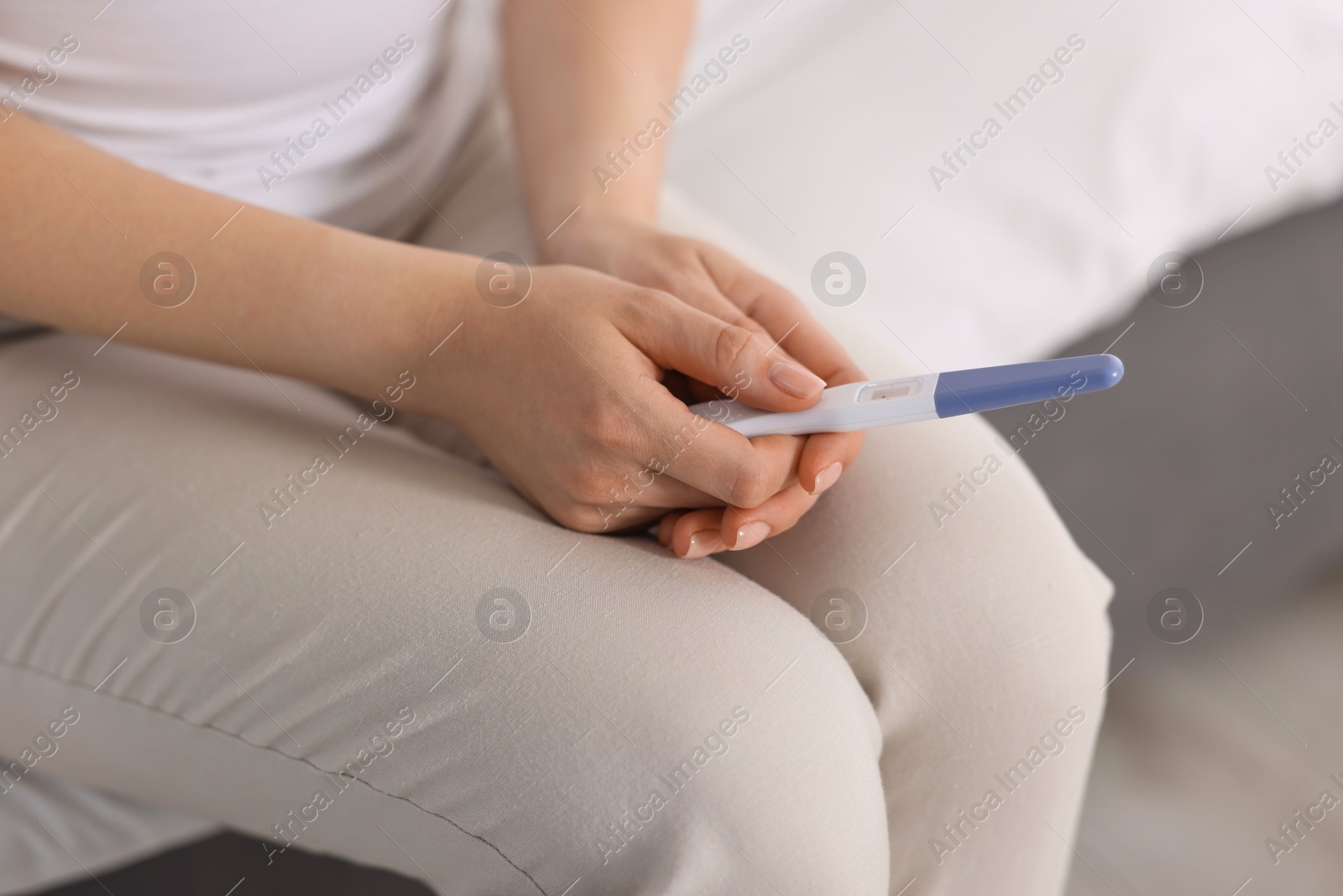 Photo of Woman holding pregnancy test in room, closeup