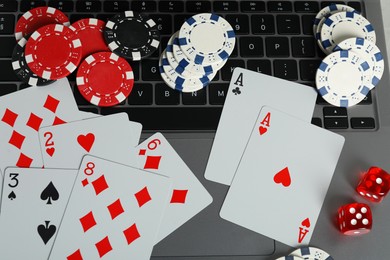 Online poker. Playing cards, dice and chips on laptop, top view