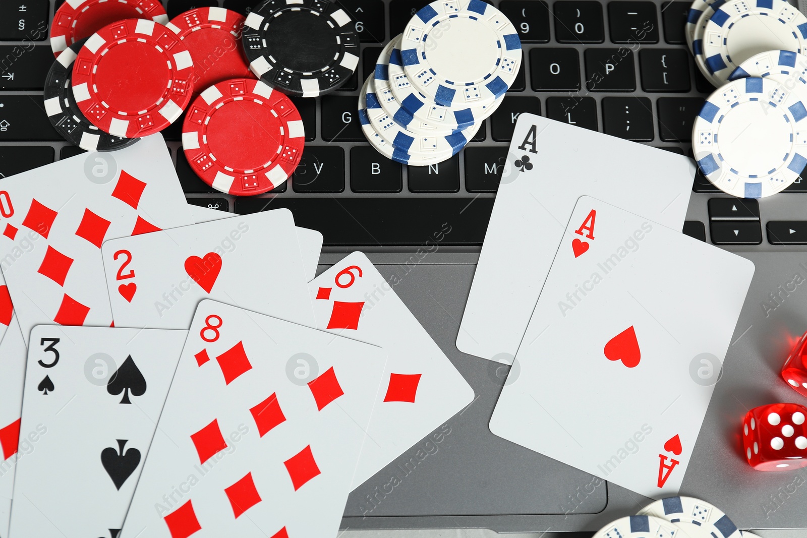 Photo of Online poker. Playing cards, chips, dice and laptop on table, top view