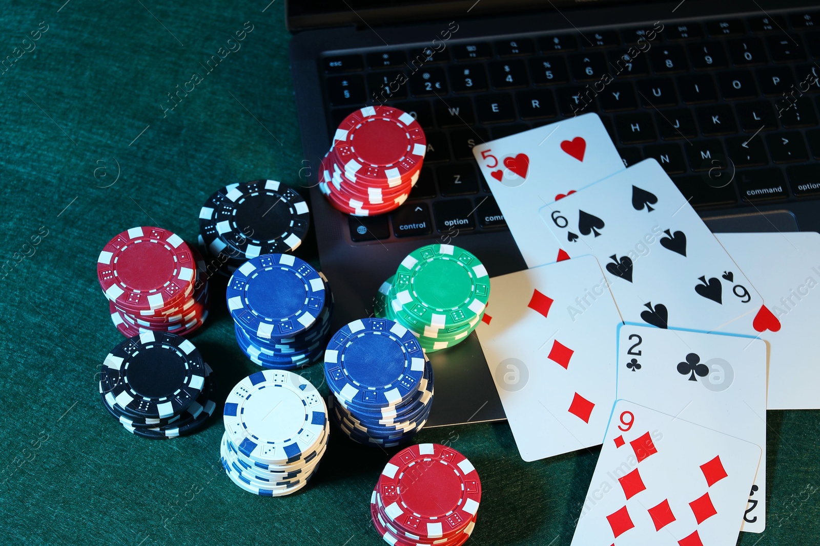 Photo of Online poker. Playing cards, chips and laptop on green table