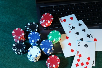 Photo of Online poker. Playing cards, chips and laptop on green table