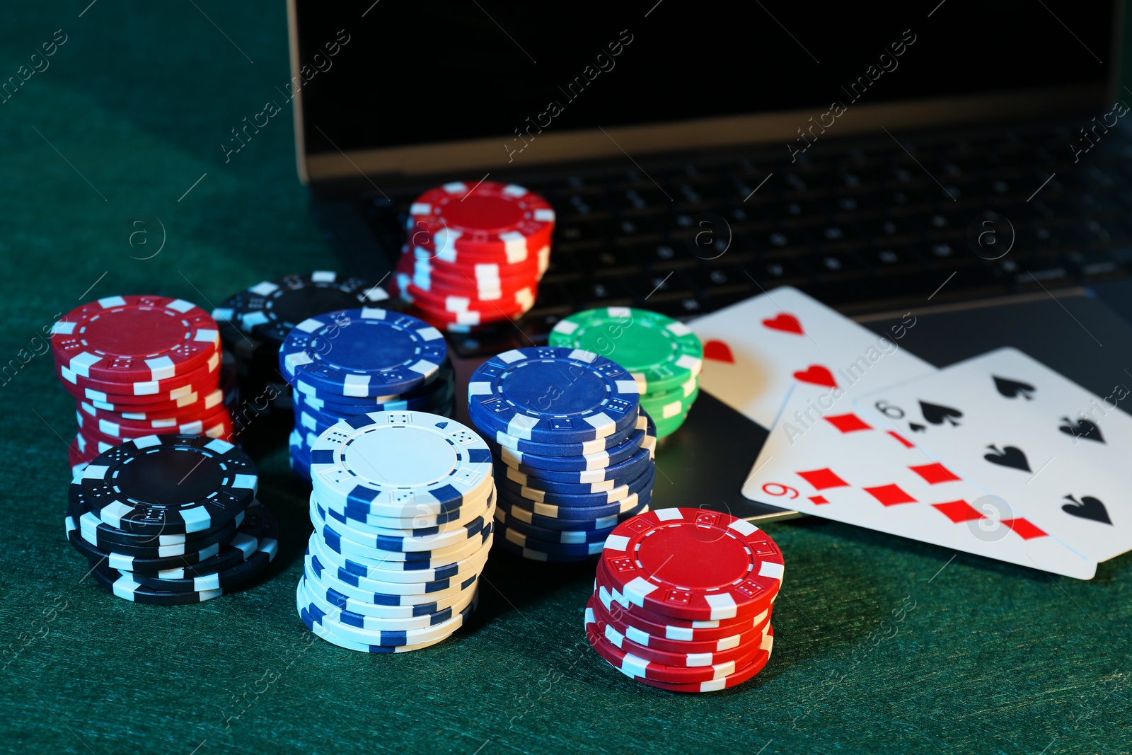 Photo of Online poker. Playing cards, chips and laptop on green table