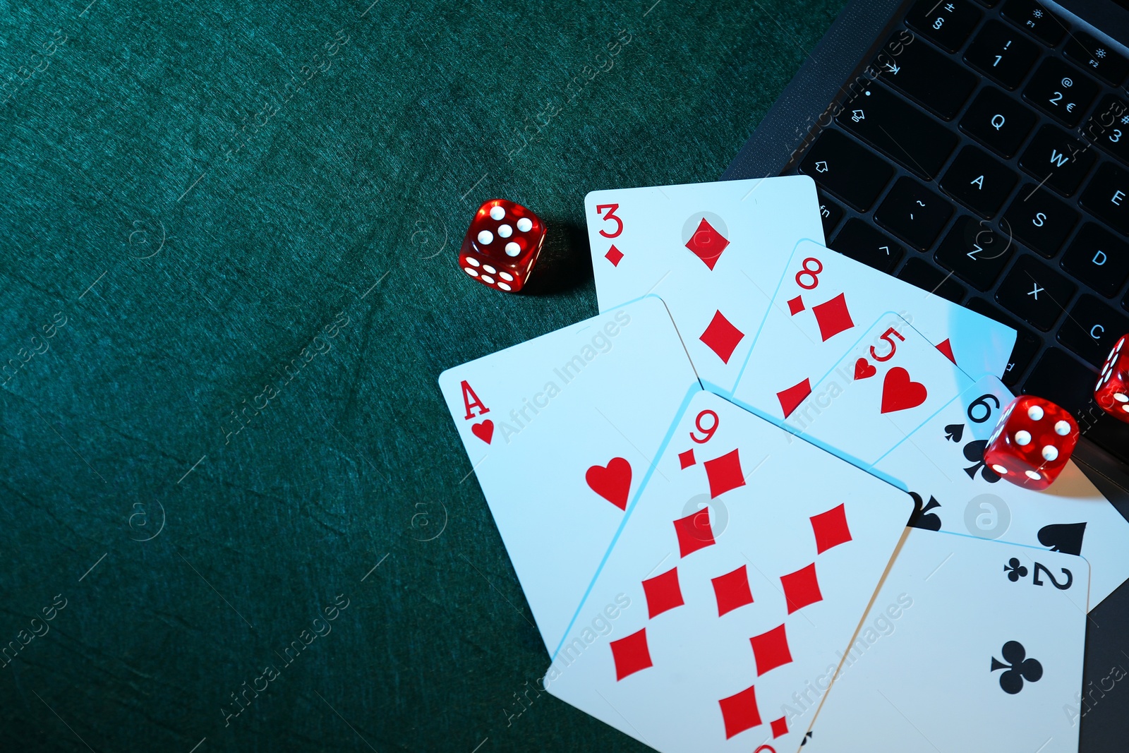 Photo of Online poker. Playing cards, dice and laptop on green table, above view. Space for text