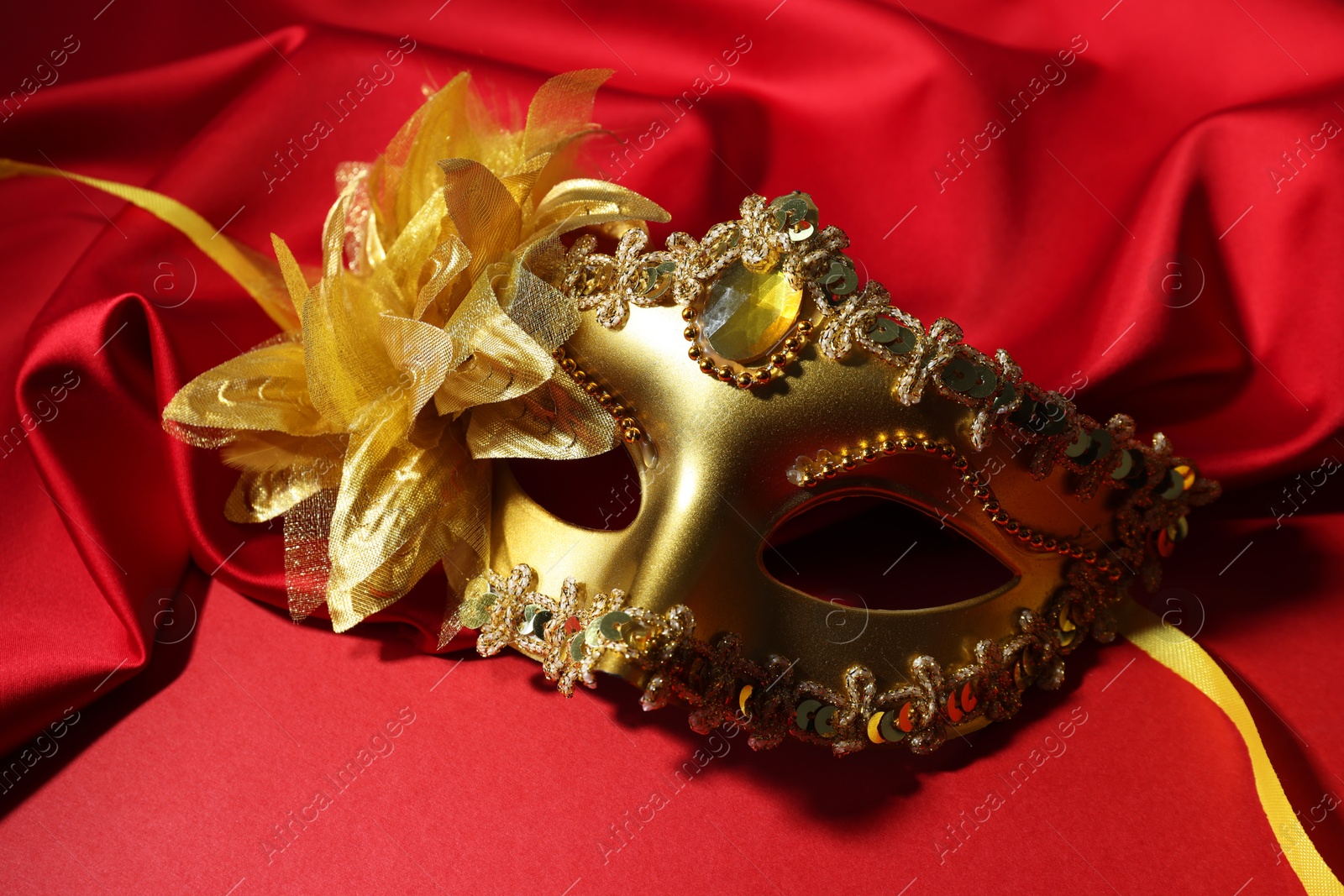 Photo of Beautiful carnival mask and fabric on red background