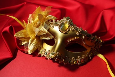 Photo of Beautiful carnival mask and fabric on red background