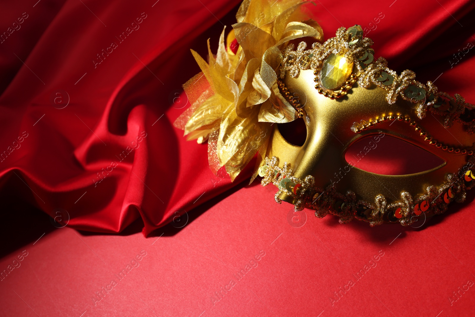 Photo of Beautiful carnival mask and fabric on red background