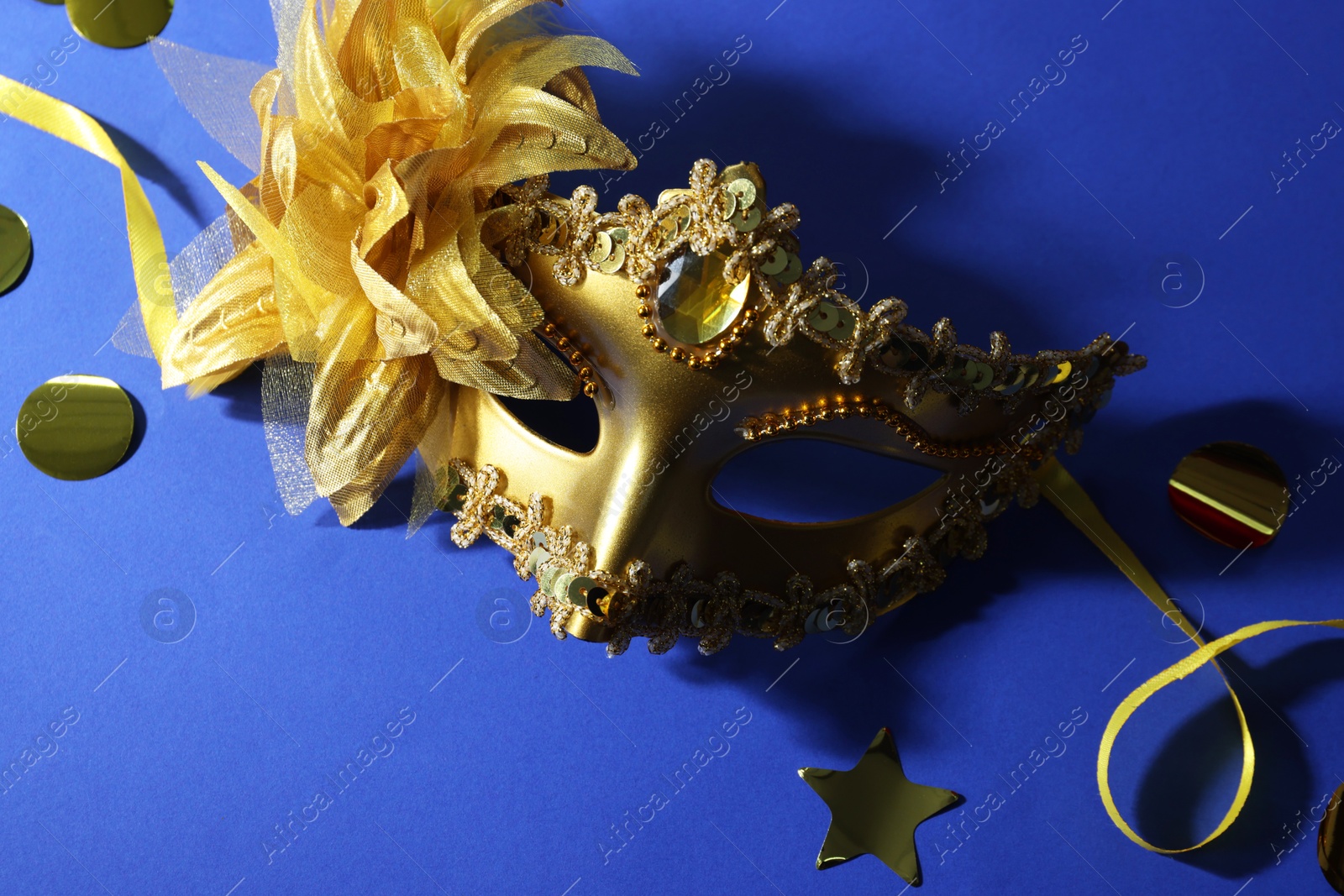 Photo of Beautiful carnival mask and confetti on blue background, top view