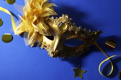 Photo of Beautiful carnival mask and confetti on blue background, top view