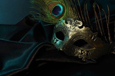 Beautiful carnival mask and peacock feather on black fabric, space for text