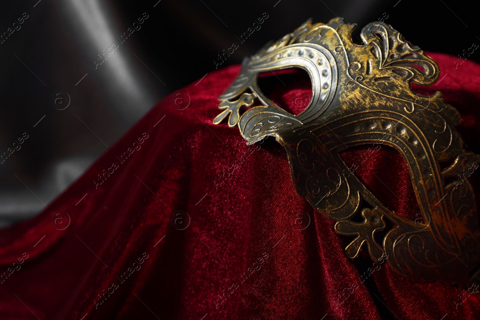 Photo of One beautiful carnival mask on red fabric, closeup