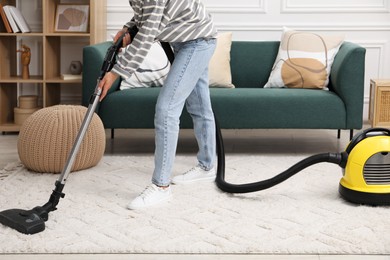 Photo of Woman cleaning carpet with vacuum in living room, closeup