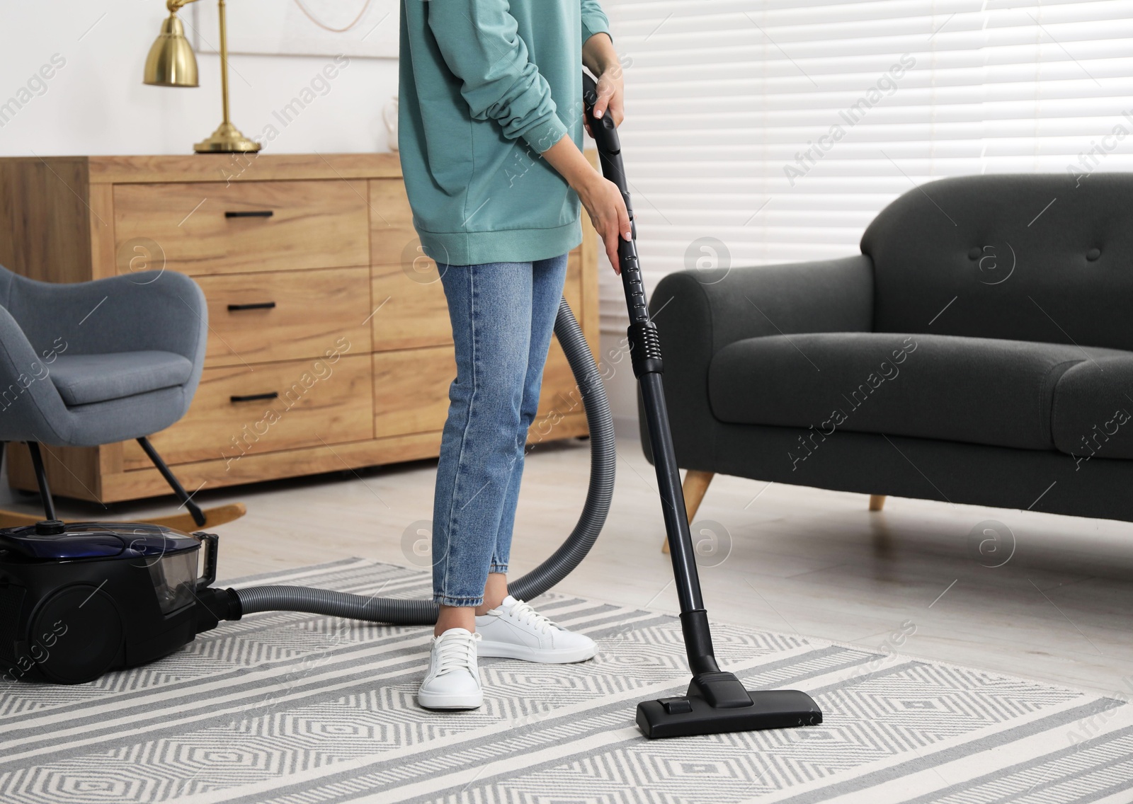 Photo of Woman vacuuming carpet at home, closeup view