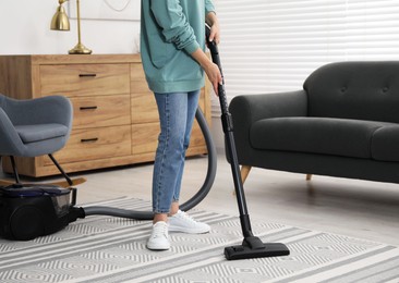 Photo of Woman vacuuming carpet at home, closeup view