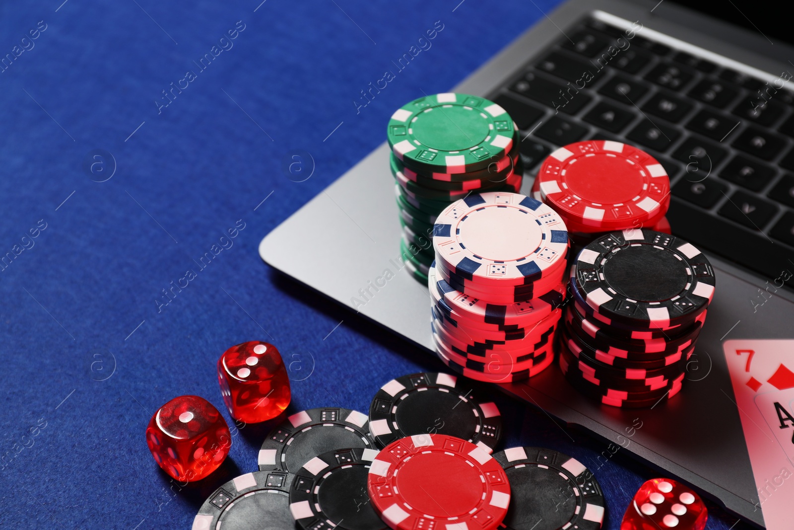 Photo of Poker chips, laptop and dices on blue table. Online game