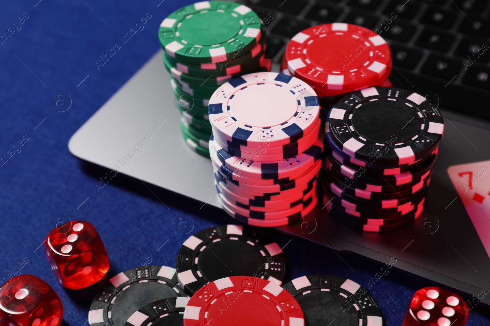 Photo of Poker chips, laptop and dices on blue table. Online game