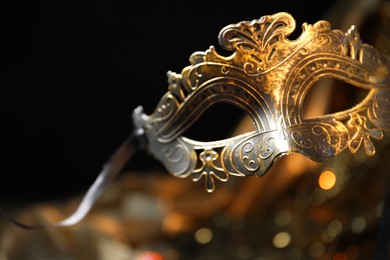 Photo of Beautiful golden carnival mask in darkness, closeup