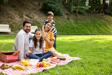 Family picnic. Happy parents and their children spending time together on green grass outdoors. Space for text