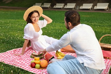 Lovely couple having picnic on green grass outdoors