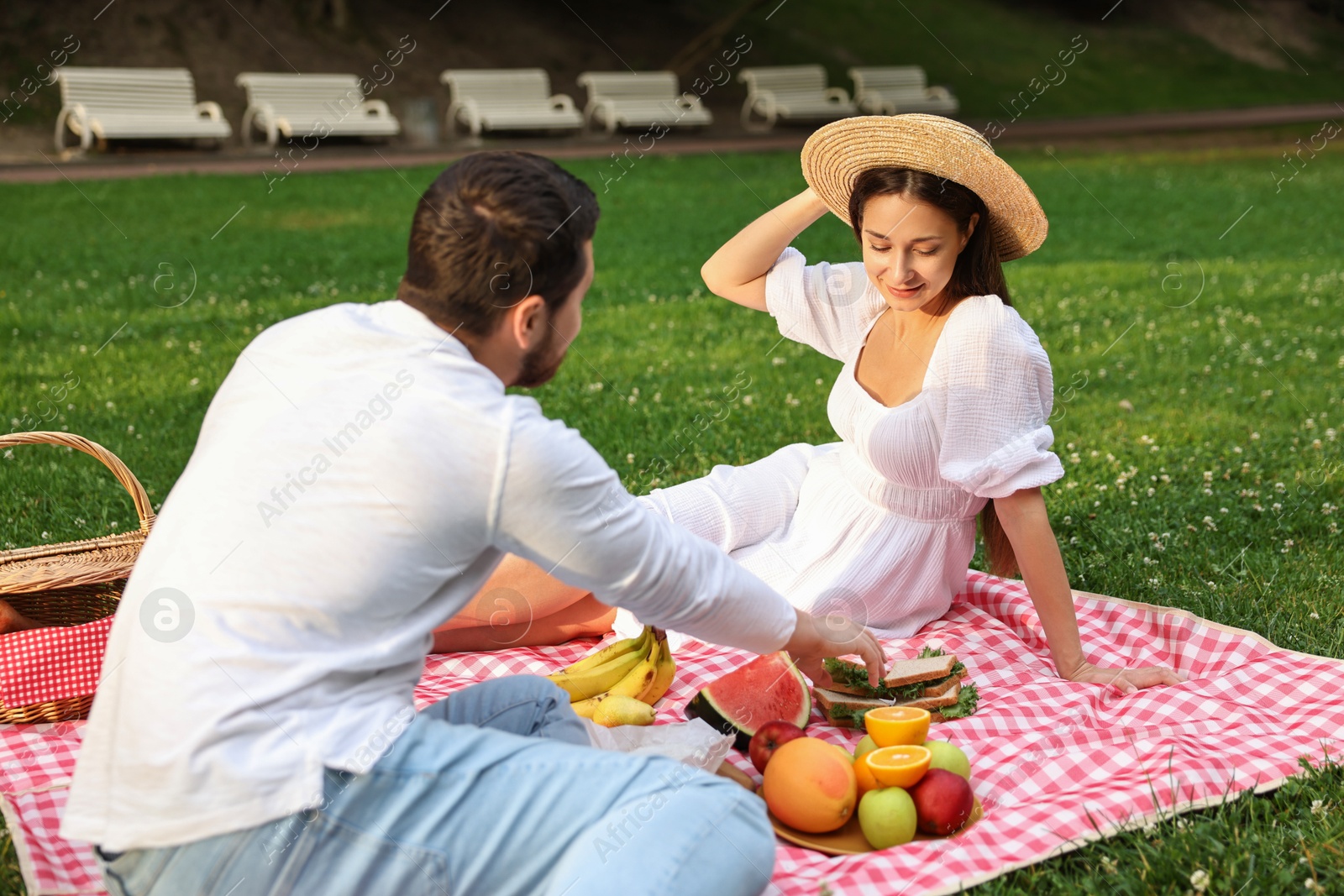 Photo of Lovely couple having picnic on green grass outdoors