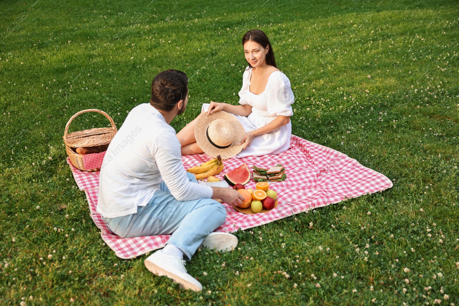 Photo of Lovely couple having picnic on green grass outdoors