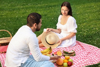 Photo of Lovely couple having picnic on green grass outdoors