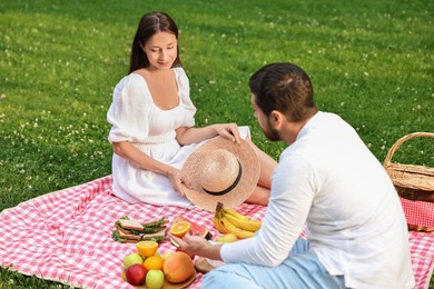 Photo of Lovely couple having picnic on green grass outdoors