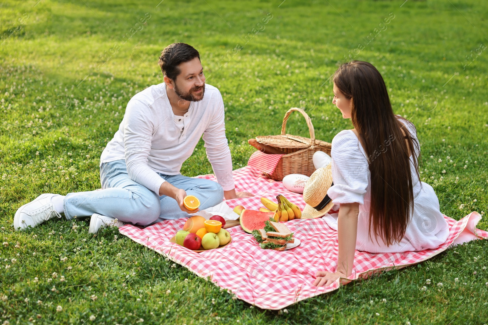 Photo of Lovely couple having picnic on green grass outdoors