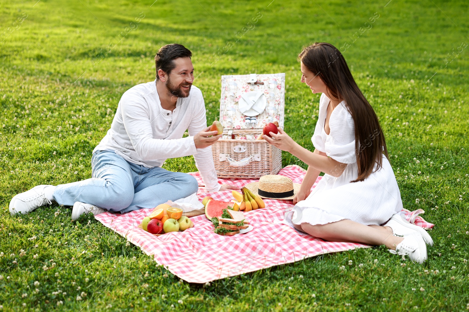 Photo of Happy couple having picnic on green grass outdoors