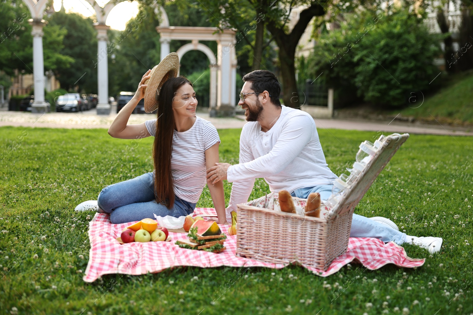 Photo of Happy couple having picnic on green grass outdoors