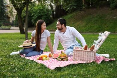 Lovely couple having picnic on green grass outdoors